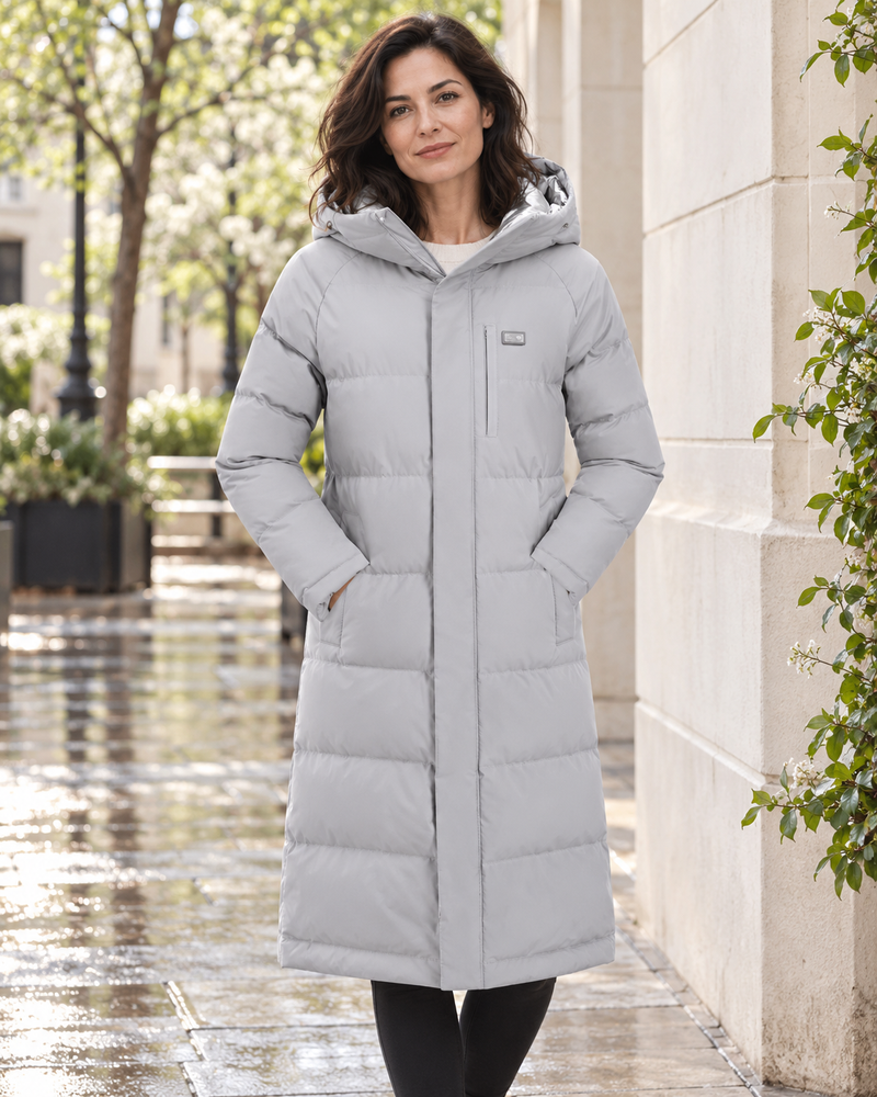 Une femme portant un manteau chauffant long gris dans une rue calme